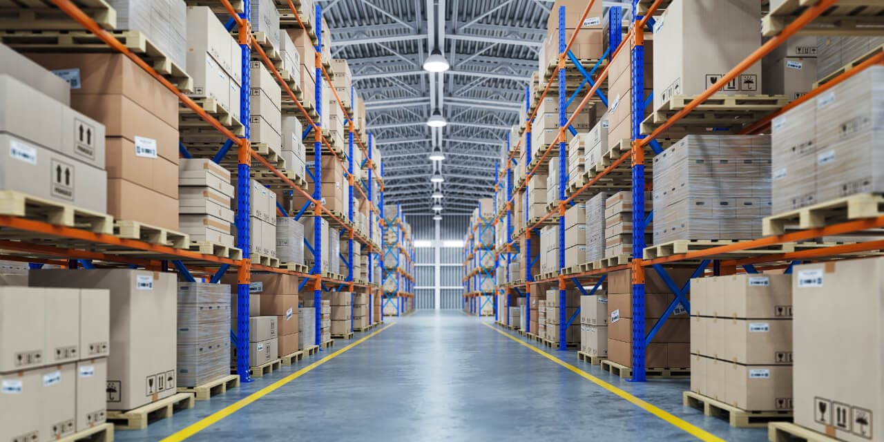 Pasillo de bodega con estanterías de cajas a ambos lados (imagen de referencia)