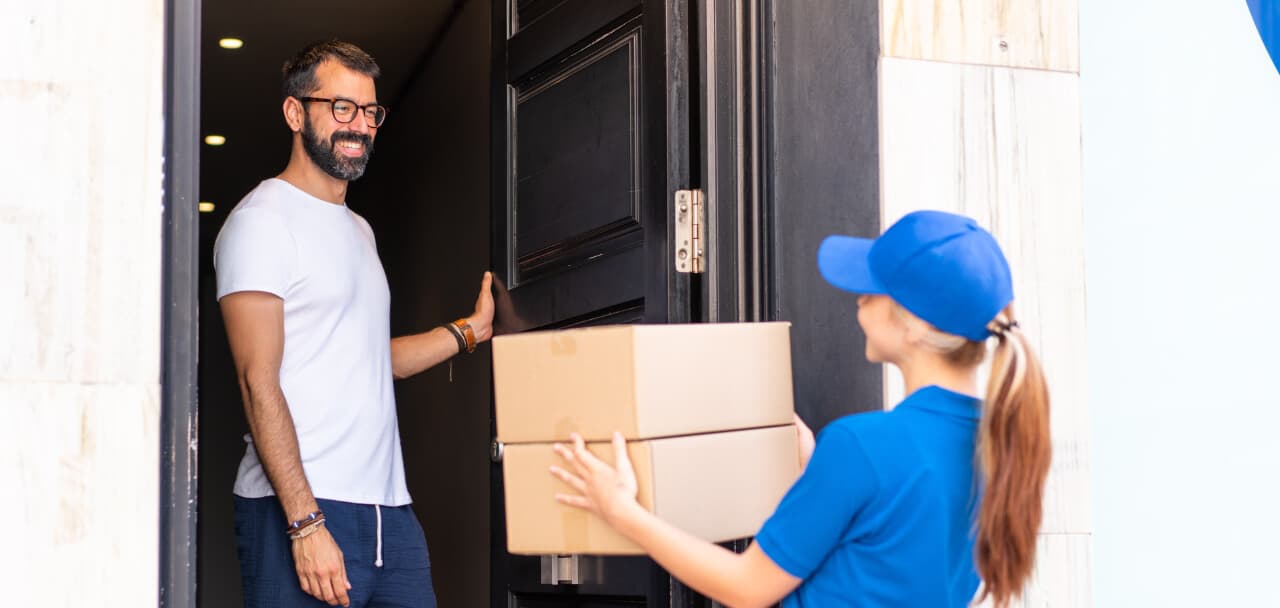 Mensajera entregando una caja a un cliente en la puerta de su casa (imagen de referencia)